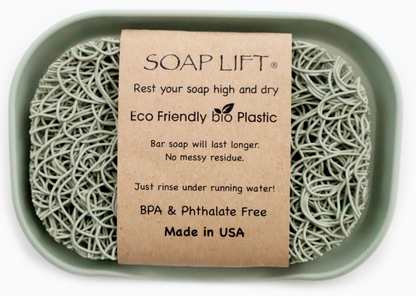 A soap lift made from eco-friendly bio plastic placed inside a green dish, featuring a label that explains its benefits for keeping soap dry and lasting longer, bpa &amp; phthalate free, and made in the usa.