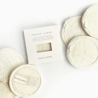 Circular exfoliating scrub pads arranged neatly next to their packaging with a minimalist design.