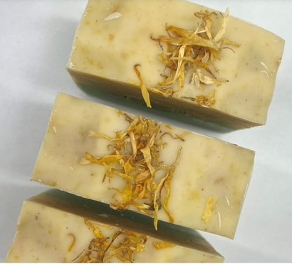 Handcrafted soap bars infused with dried flower petals on a neutral background.